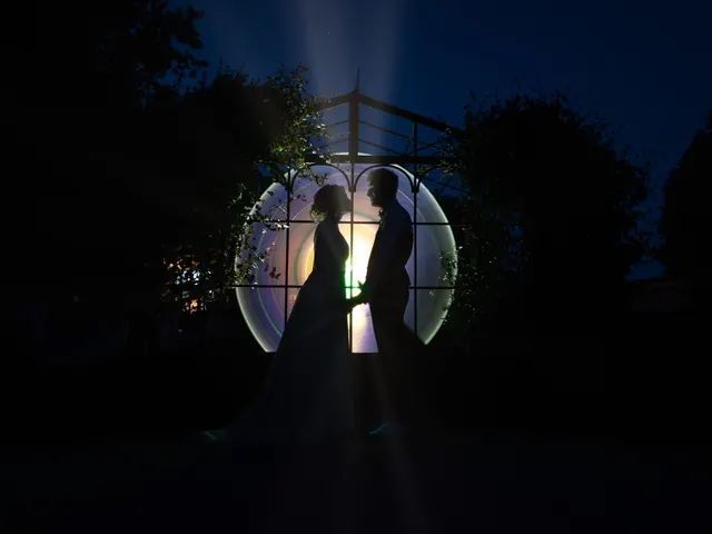 Light painting de mariage : les mariés en silhouette devant une verrière illuminée