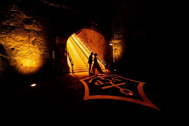 Silhouette des mariés au pied de l'escalier lumineux d'une cave de Champagne – Frédéric Leroux, photographe de mariage à Reims